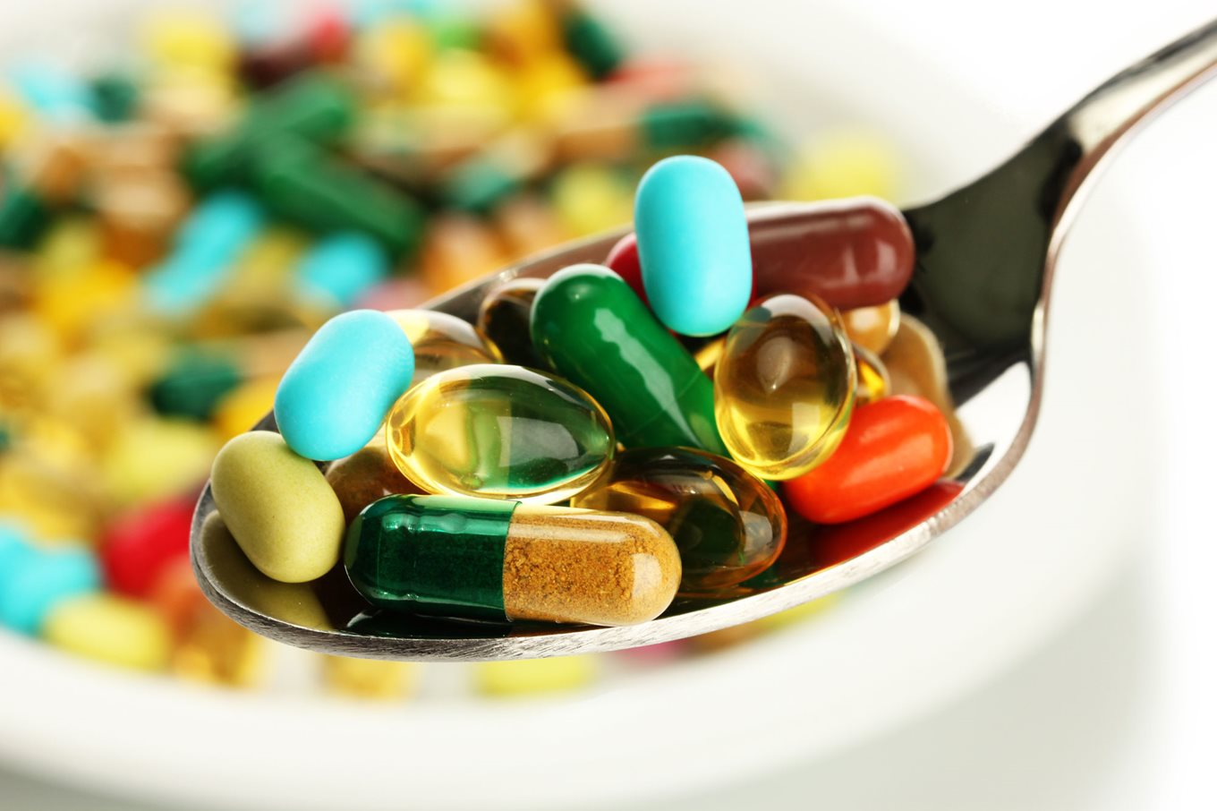 Spoon full of various coloured/sized food supplement tablets