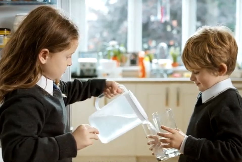 Two children pouring water into glasses