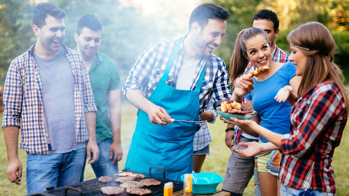 Cooked barbequed burgers on an outside table with a meat thermometer reading the correct temperature to safely eat, 75 degrees celcius.
