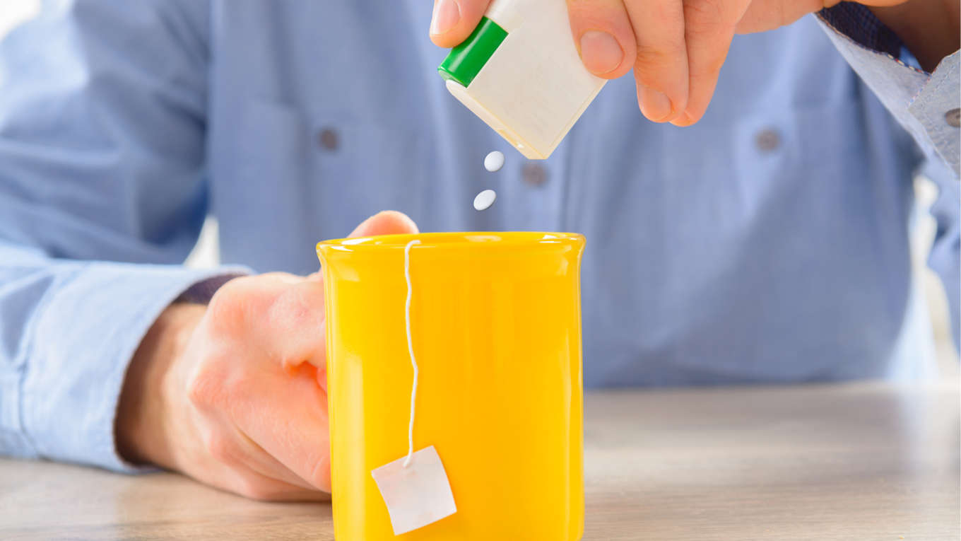 Image of a person adding artificial sweetener to their drink